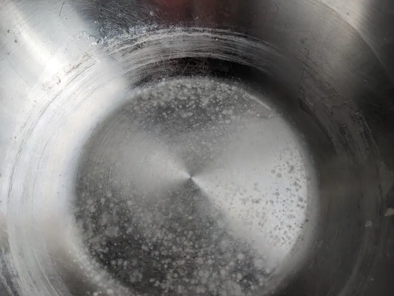 Thick white limescale deposits coating the inside of a metal kettle base